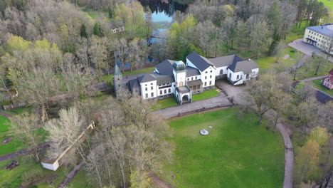 Manor-of-Jaungulbene-with-green-grass-and-water-pond-behind,-aerial-view