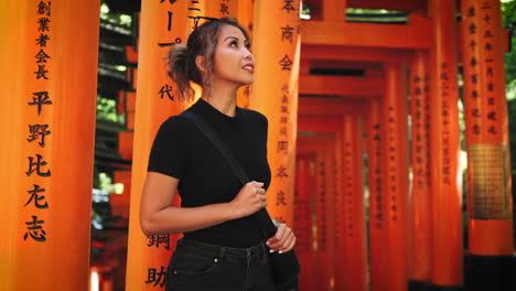 Asian-Woman-in-black-top-and-jeans,-explores-the-Fushimi-Inari-Shrine