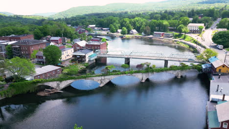 The-bridge-of-flowers-and-town-of-shelburne-falls-on-a-sunny-day,-aerial-view