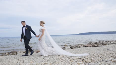 Bride-and-groom-walk-down-beach-holding-hands