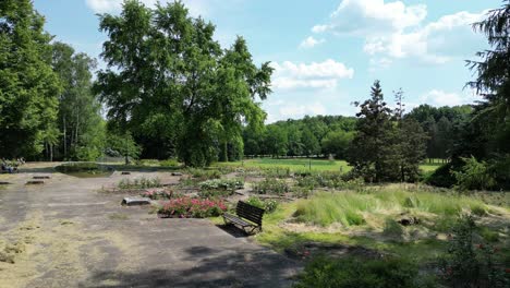 Flowers-in-park-during-a-beautiful-summer-day-surrounded-by-lush-greenery,-grass-and-trees-under-a-clear-blue-sky