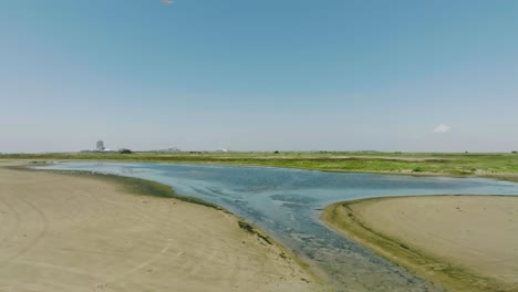 An-aerial-drone-view-of-a-tidal-pool-with-seagulls-taking-flight-on-East-Beach-in-Galveston,-Texas