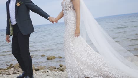 Bride-and-groom-walk-down-beach-clasping-hands