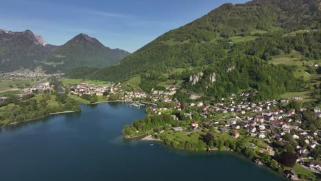 Drone-advancing-over-the-picturesque-village-of-Wessen-in-Switzerland,-nestled-along-the-shores-of-Lake-Walensee-amidst-the-Swiss-Alps