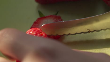 Side-View-of-Female-Hand-Cutting-Fresh-Red-Strawberry-in-Half