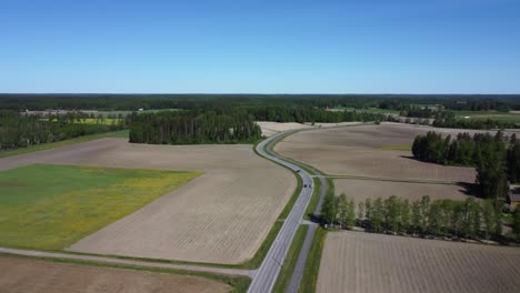 Aerial-follows-country-highway-traffic-through-agriculture-crop-fields