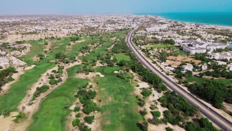 Eine-Luftaufnahme-Eines-Golfplatzes-Neben-Einem-Strand-Mit-Vielen-Bäumen-Und-Grünem-Gras-Von-Oben-In-Tunesien-Djerba