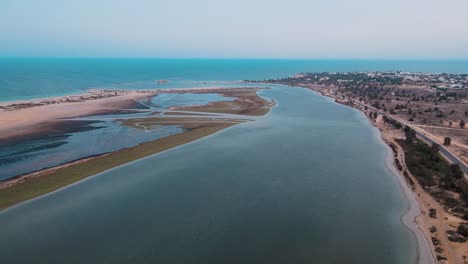 Eine-Luftaufnahme-Eines-Strandes-Mit-Wasser-Und-Sand,-Das-Wasser-Ist-Ruhig-Und-Blau