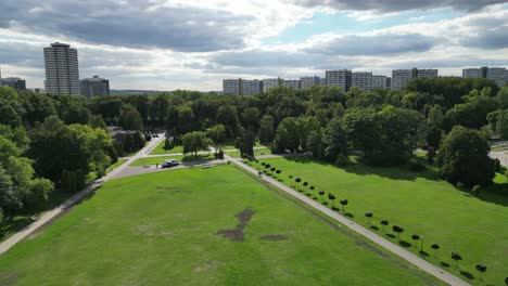 Junto-Al-Parque-Durante-Un-Hermoso-Día-De-Verano-Rodeado-De-Exuberante-Vegetación,-Césped-Y-árboles-Bajo-Un-Cielo-Azul-Con-Edificios-En-La-Distancia