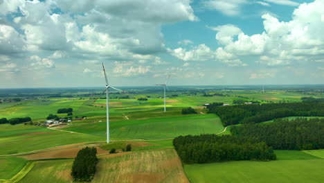 Luftaufnahmen,-Die-Eine-Reihe-Von-Windturbinen-Zeigen,-Die-Hoch-über-Grünen-Landwirtschaftlichen-Feldern-Unter-Einem-Teilweise-Bewölkten-Himmel-Stehen