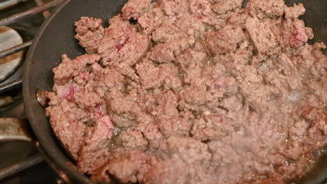 Zoom-in---ground-beef-cooking-in-a-frying-pan-on-a-gas-stove-top