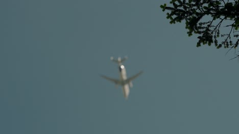 Airplane-flying-high-in-the-sky,-seen-from-below,-against-a-backdrop-of-clouds