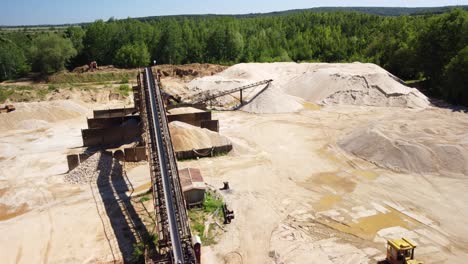 Sand-Heaps,-Machinery,-and-Equipment-Within-an-Aged-Sand-Mine-Near-the-Town-of-Prudnik,-Poland---Aerial-Drone-Shot