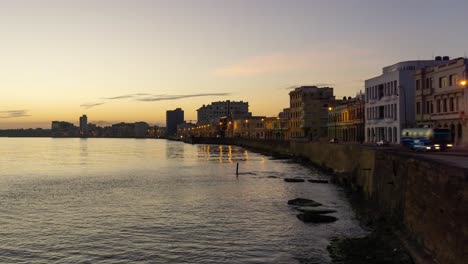 Hermosa-Vista-De-Lapso-De-Tiempo-De-La-Vieja-Ciudad-De-La-Habana,-Capital-De-Cuba,-Junto-A-La-Costa-Del-Océano-Durante-Un-Vibrante-Amanecer-Soleado-Y-Colorido