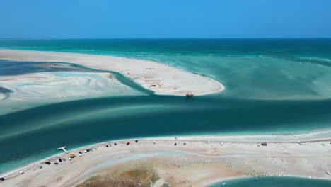 Una-Vista-Aérea-De-La-Escena-De-La-Playa-Acuática-De-Hassi-El-Jerbi-Con-Personas-Y-Barcos-En-El-Agua-En-Zarzis-Túnez