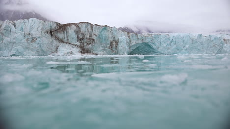 Crumbled-Pieces-of-Ice-Under-Glacier-in-Cold-Arctic-Sea-Water,-Low-Angle-View-From-Moving-Boat