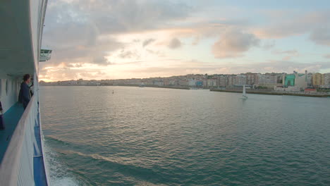 POV-along-starboard-rail-of-ferry-approaching-harbor-at-sunset,-wide