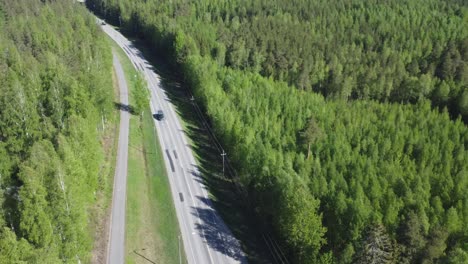 Rotating-aerial-tracks-car-driving-on-northern-green-forest-highway