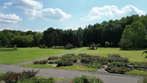 Bowers-in-park-during-a-beautiful-summer-day-surrounded-by-lush-greenery,-grass,-flowers-and-trees-under-a-clear-blue-sky