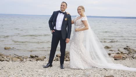 Bride-and-groom-stand-together-on-beach