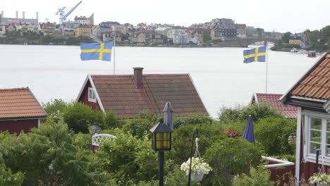 Flag-Day-and-Swedish-Red-Summer-Cottages-with-Traditional-Gardens,-Pan-shot