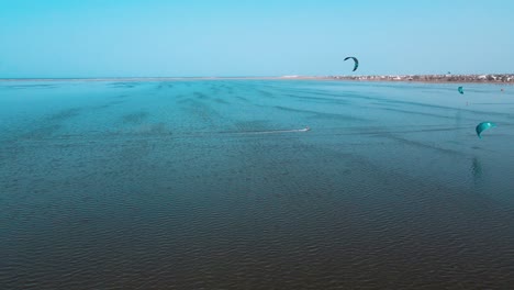 Eine-Luftaufnahme-Eines-Gewässers-Mit-Menschen-Beim-Windsurfen-Und-Parasailing,-Kitesurfen-Im-Meer-Der-Lagune-Von-Djerba-In-Tunesien