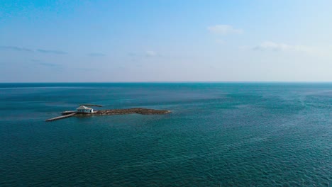 An-aerial-view-of-el-biben-island-with-a-pool-and-hosting-houses-sits-in-the-middle-of-the-ocean-with-palm-trees-on-it,-surrounded-by-water-creating-a-beautiful-atmosphere