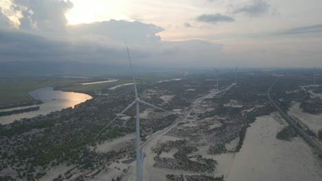 Aerial-shots-of-windmills-farm-on-sandy-beach-next-to-a-big-river-in-Quang-Binh,-Viet-Nam