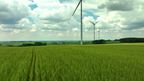 Luftaufnahmen-Zeigen-Windturbinen,-Die-Hoch-über-Grünen-Feldern-Unter-Einem-Teilweise-Bewölkten-Himmel-Stehen