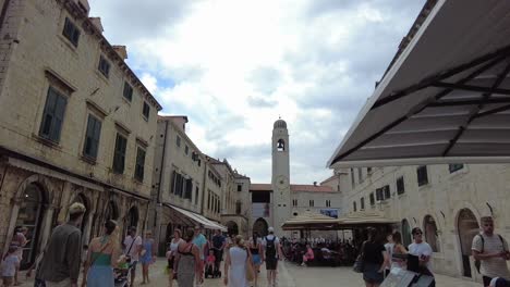 Walking-through-the-square-of-Dubrovnik's-old-town,-merging-with-fellow-travelers-and-explorers,-capturing-the-essence-of-cultural-immersion-and-historic-exploration