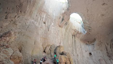 Chamber-grotto-lit-by-the-eyes-of-God-as-tourists-exploring-karst-cave