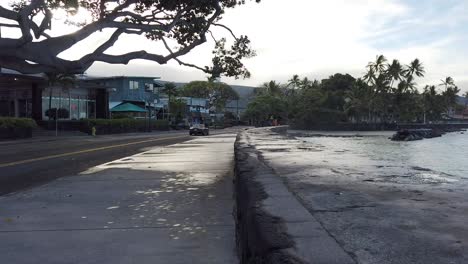 Black-convertible-slowly-drive-by-beach-road-walkway-early-morning