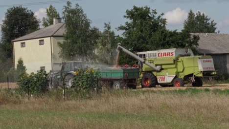 Transferring-freshly-mown-grain-from-a-combine-to-a-trailer-towed-to-the-tractor