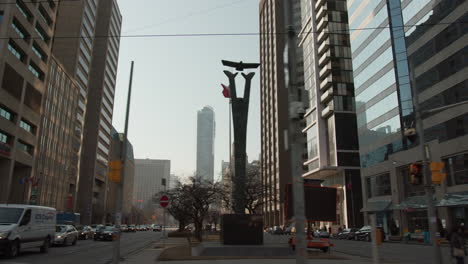 Driving-down-Dundas-West-on-a-busy-sunny-evening-in-Toronto,-Canada-with-the-CN-tower-in-the-background