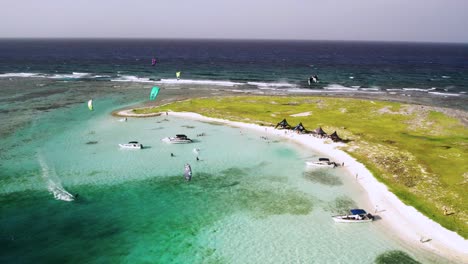 A-vibrant-beach-scene-with-boats-and-kite-surfers-on-a-sunny-day,-aerial-view