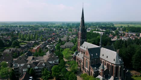 Drone-captures-the-picturesque-view-of-Budel,-featuring-Onze-Lieve-Vrouw-Church,-quaint-streets,-and-rooftops