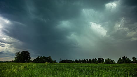 Powerful-storm-clouds-flowing-above-rural-landscape,-time-lapse-view