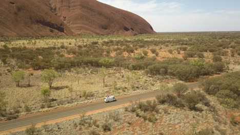 Uluru-Ayers-Rock,-Australia-with-drone-wide-orbit-around-a-white-campervan