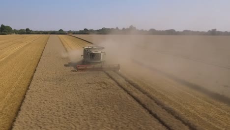 Harvest-low-arc-shot-around-front-of-Claas-Harvester-through-crop-dust