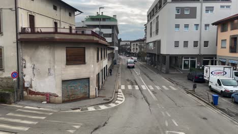 Ambulance-with-Flashing-Lights-Approaching-from-Old-Buildings-and-Cloudy-Sky