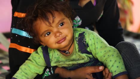 Vuela-Sobre-La-Cara-De-Un-Niño-Indio-En-Brazos-De-Su-Madre,-Aldea-De-Noondpura-En-Rajasthan