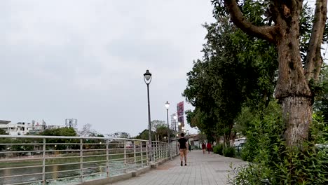 People-walking-near-lake-walkway-in-early-morning-cloudy-weather,-Full-HD