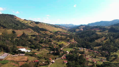 Luftbild-Drohne-Mit-Landschaftsansicht-Der-Nachbarschaftslage-Von-Delfim-Moreira-Im-Tal,-Ländliche-Vororte-Mit-Bauernhöfen-Und-Gebirgswald,-Minas-Gerais,-Brasilien