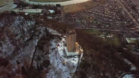 Drone-orbital-shot-of-William-Wallace-Monument-in-Stirling,-Scotland,-during-blue-hour-on-a-cold-winter-evening