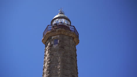 Ancient-Estepona-light-house-against-blue-sky,-tilt-up-view