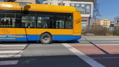 Low-floor-Articulated-Trolleybus-Moving-On-The-Street,-Passing-By-Business-Buildings-In-Czech-Republic