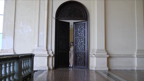 Puerta-De-Madera-Ornamentada-En-El-Histórico-Palacio-De-Gia-Long,-Ciudad-Ho-Chi-Minh,-Vietnam-Con-Mujeres-Entrando