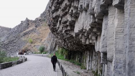 Una-Turista-Camina-Hacia-La-Cámara-En-Una-Sinfonía-De-Piedras,-Columnas-De-Basalto.