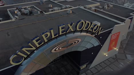 360-reveal-of-Cineplex-Odeon-movie-theatre-cinema-exterior-with-signage-and-vacant-parking-lot