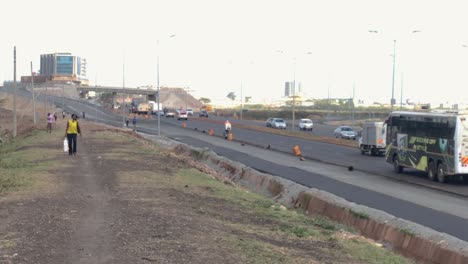 African-people,-pedestrians-walking-roadside,-highway-traffic,-Nairobi,-Kenya